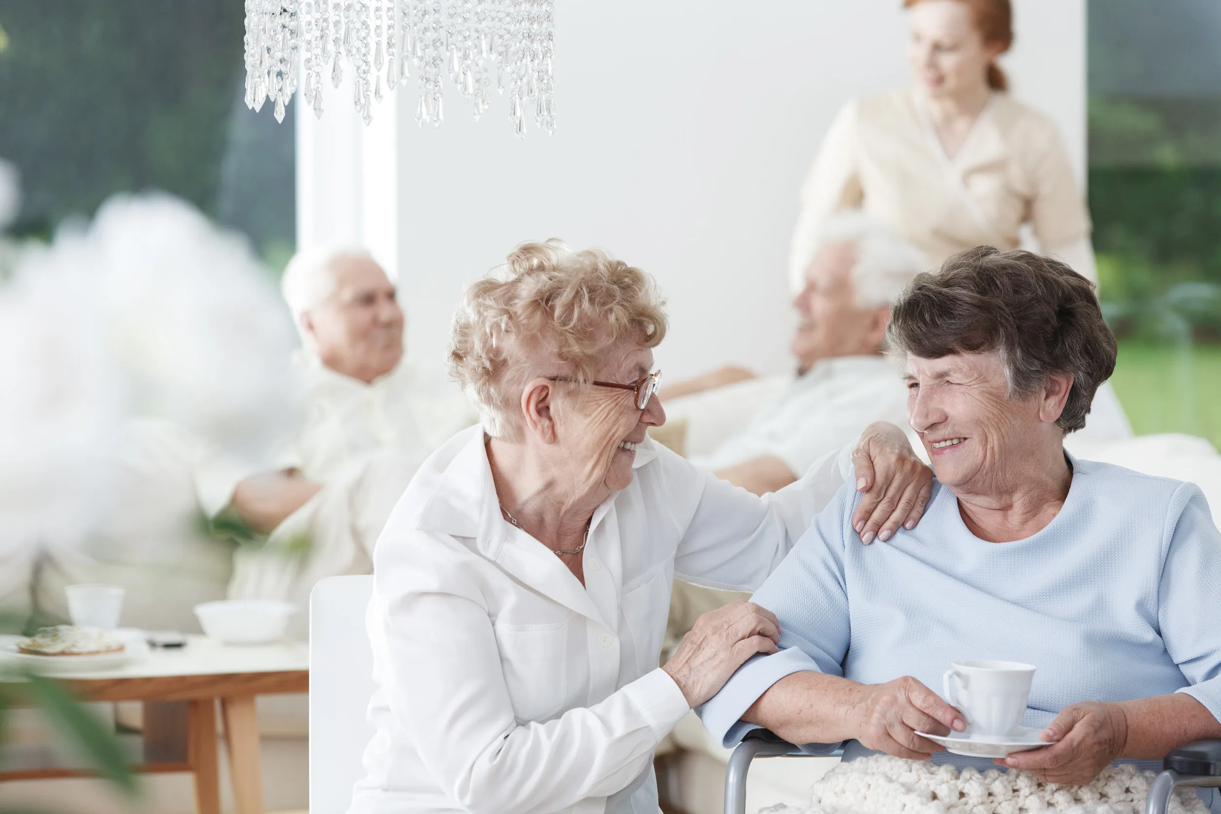 Two senior women friends talking and laughing over a cup of tea Two senior women friends talking and laughing over a cup of tea